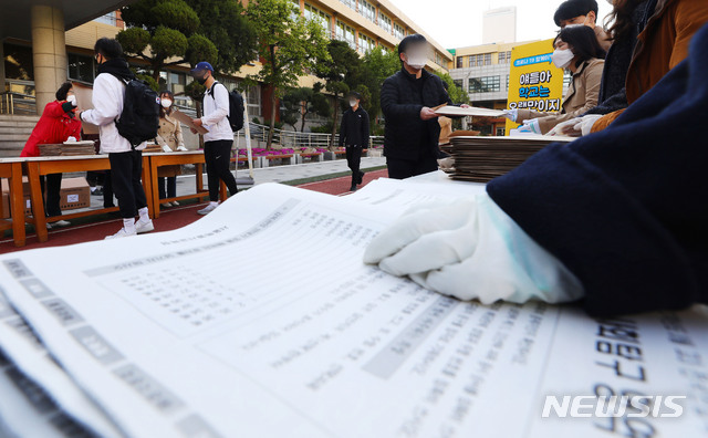 [서울=뉴시스]홍효식 기자 = 2020학년도 3월 전국연합학력평가가 실시되는 24일 오전 서울 영등포구 여의도고에서 고3 학생들이 워킹 스루 방식으로 시험지를 배부 받고 있다. 2020.04.24. yesphoto@newsis.com