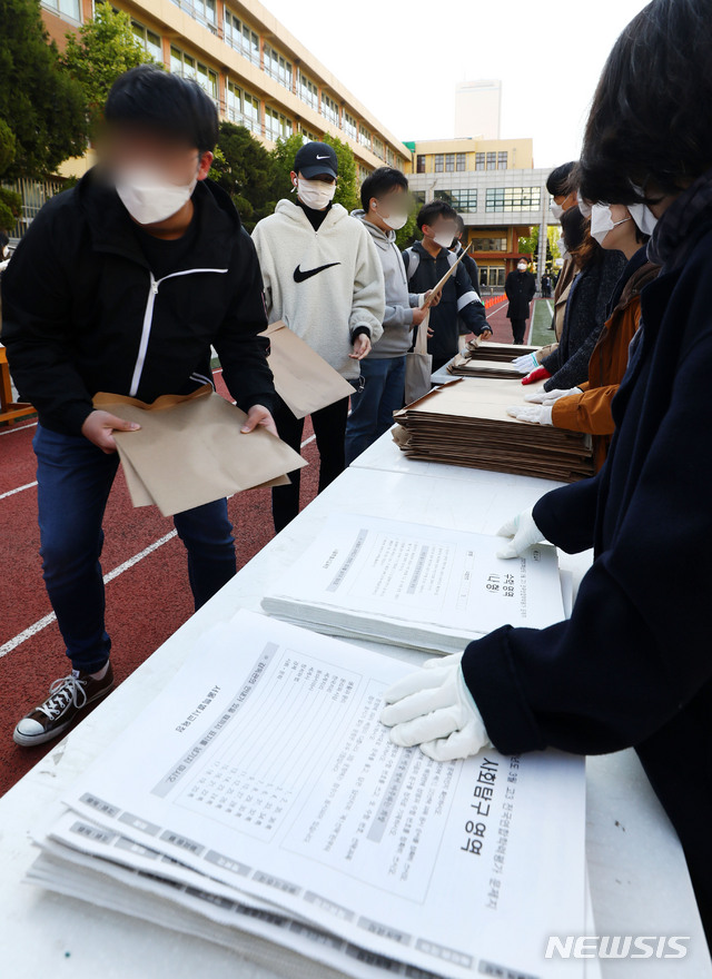 [서울=뉴시스]홍효식 기자 = 2020학년도 3월 전국연합학력평가가 실시되는 24일 오전 서울 영등포구 여의도고에서 고3 학생들이 워킹 스루 방식으로 시험지를 배부 받고 있다. 2020.04.24. yesphoto@newsis.com