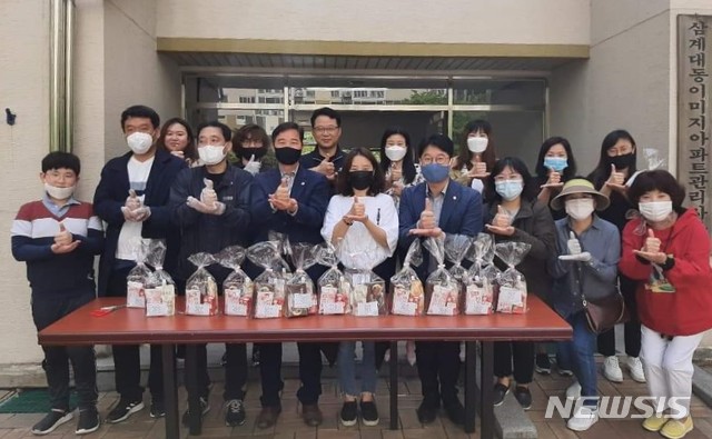 [창원=뉴시스] 경남 창원시 마산회원구 삼계대동이미지아파트입주자대표회 관계자들이 2일 어린이날 선물로 준비한 과자 꾸러미를 나눠준 후 송순호 도의원, 이우완 시의원 등과 '덕분에 챌린지' 동참 손동작으로 기념촬영을 하고 있다.(사진=송순호 페이스북 제공) 2020.05.02. photo@newsis.com