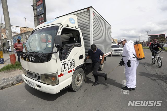[보고타=AP/뉴시스]6일(현지시간) 콜롬비아 보고타에서 한 택시 운전사(오른쪽)가 지나가던 트럭에 신종 코로나바이러스 감염증(코로나19) 예방 소독을 하고 있다. 이 남성은 재봉사인 부인 에르난데스와 자신의 친구와 함께 코로나19 여파로 일이 줄면서 차 한 대당 75센트를 받는 소독 서비스로 생계를 잇고 있다. 2020.05.07.