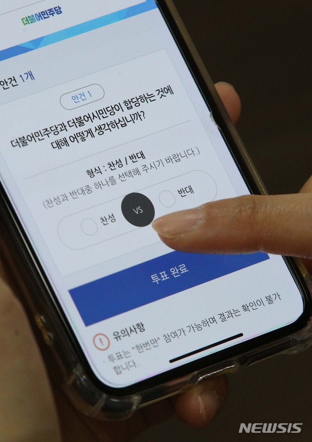 [서울=뉴시스] 김진아 기자 = 더불어민주당 당원이 7일 오전 국회에서 스마트폰으로 더불어민주당-더불어시민당 합당 여부를 묻는 권리당원 투표를 하고 있다. 2020.05.07.&nbsp; photo@newsis.com