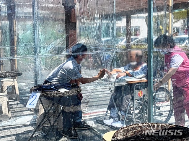 [울산=뉴시스] 구미현 기자 = 8일 어버이날을 앞두고 울산 울주군 삼남면 이손요양병원 안심면회실을 찾은 방문객이 아버지를 병문안하고 있다. 아버지와 아들은 비닐을 사이에 두고 마스크를 착용한채 서로 얼굴을 보며 대화하고 있다. 2020.05.08. photo@newsis.com