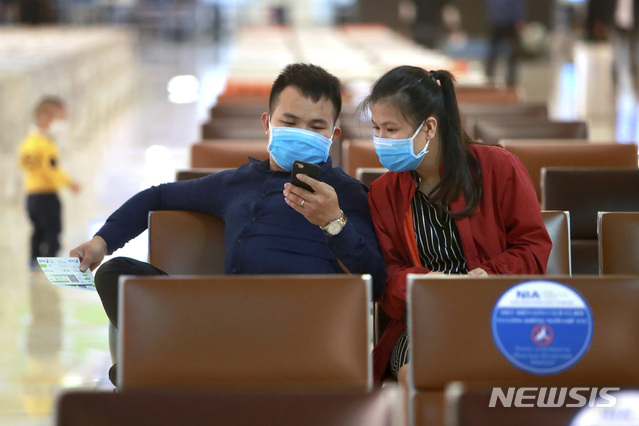 [하노이=AP/뉴시스]7일(현지시간) 베트남 하노이 공항 출국장에 신종 코로나바이러스 감염증(코로나19) 예방을 위해 마스크를 쓴 남녀가 휴대전화를  들여다보고 있다. 베트남은 지난 3주간 신종 코로나바이러스 감염증(코로나19) 확진 사례가 보고되지 않으면서 학교, 기업, 공장, 관광지 등을 다시 열었으나 이날 17명의 해외 유입 자국민 코로나19 환자가 생겨 비상이 걸렸다. 2020.05.08. 