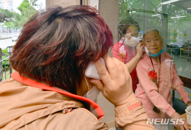 [광주=뉴시스] 변재훈 기자 = 어버이날인 8일 광주 광산구 우산동 한 요양병원에서 입원환자와 가족들이 비접촉 면회를 하고 있다. 병원 측은 코로나19 확산 방지를 위해 건물 외벽 유리창을 사이에 두고 무선 전화로 대화할 수 있는 비접촉 면회실을 마련했다. 2020.05.08.wisdom21@newsis.com