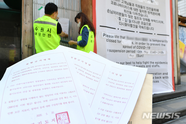[수원=뉴시스] 11일 수원시 직원들이 한 유흥주점에 집합금지 명령 고지문을 부착하고 있다.