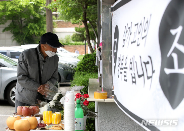 [서울=뉴시스] 박미소 기자 = 지난 5월12일 서울 강북구의 한 아파트 경비실 앞에서 한 시민이 고 최모 경비원를 위한 추모 공간을 바라보고 있다. 2020.05.12. misocamera@newsis.com