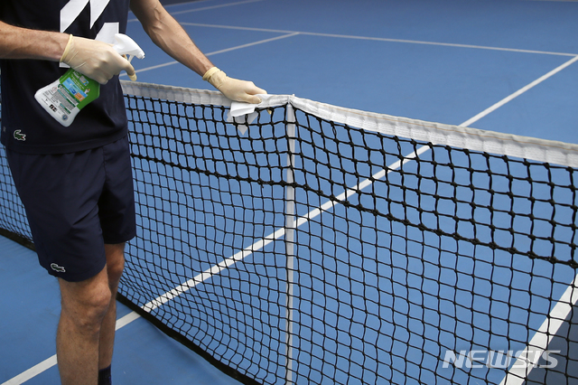 [파리=AP/뉴시스]니콜라 마위(프랑스)가 13일(현지시간) 프랑스 파리의 프랑스오픈 경기장 인근 프랑스 테니스 연맹 센터에서 팀 의료진과 코트 트레이너들이 지켜보는 가운데 훈련하면서 그물을 소독하고 있다. 2020.05.14.