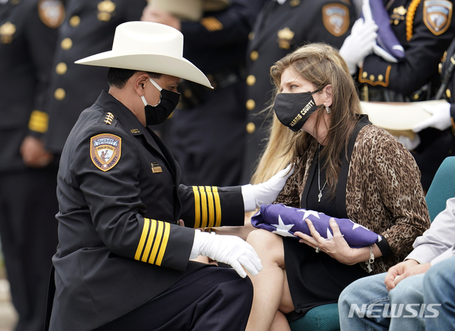  [험블( 미 텍사스주)=AP/뉴시스] 휴스턴시가 포함된 해리스 카운티의 보안관 에드 곤살레스가 지난 해 5월 14일 코로나19로 숨진 동료 보안관의 장례식에서 가족들을 위로하고 있다.