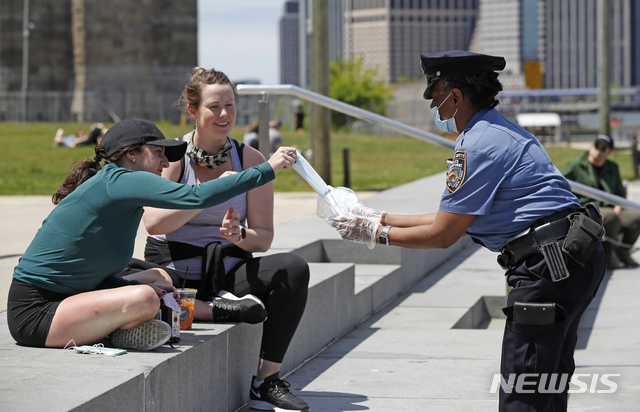 [뉴욕=AP/뉴시스]17일(현지시간) 미국 뉴욕에서 뉴욕시경(NYPD) 학교안전과 경찰이 신종 코로나바이러스 감염증(코로나19)을 막기 위한 마스크를 시민들에게 나눠주고 있다. 2020.05.18.&nbsp; 