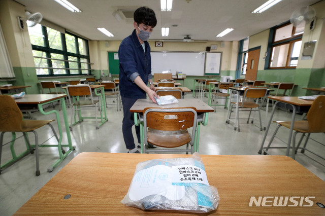 [서울=뉴시스]김병문 기자 = 고등학교 3학년 등교일을 하루 앞둔 19일 오후 서울 종로구 경복고등학교 3학년 교실에서 교사가 책상에 마스크와 손소독제 세트를 놓고 있다. 2020.05.19. dadazon@newsis.com