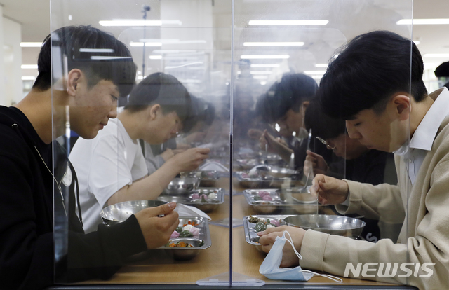 [청주=뉴시스] 인진연 기자 = 고3 학생들이 올해 첫 등교를 시작한 20일, 충북 청주 봉명고등학교에서 발열확인을 마친 학생들이 가림막을 두고 마주 앉아 조용히 급식을 먹고 있다. 2020.05.20. photo@newsis.com