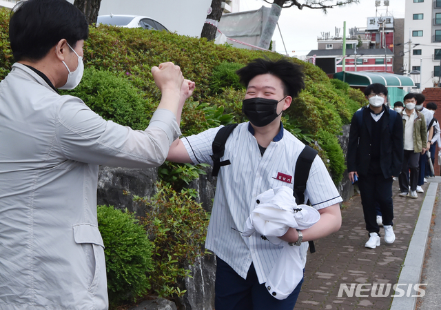 [수원= 뉴시스] 김종택기자 = 고등학교 3학년 등교가 시작된 20일 오전 경기 수원시 팔달구 수원고등학교에서 고3 학생이 교사와 반갑게 주먹인사를 하고 있다. 2020.05.20.semail3778@naver.com