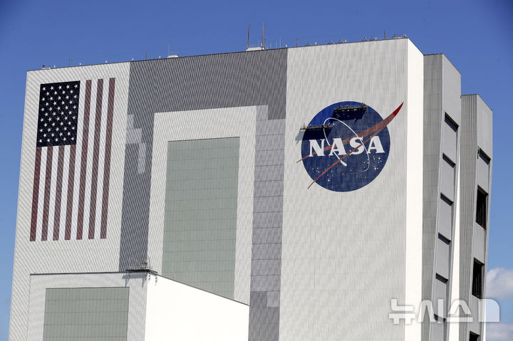 [케이프커내버럴(플로리다)=AP/뉴시스]2020년 5월20일 미 플로리다주 케이프커내버럴 케네디우주센터의 조립 건물 외벽 미 항공우주국(NASA) 로고를 노동자들이 손 보는 모습.