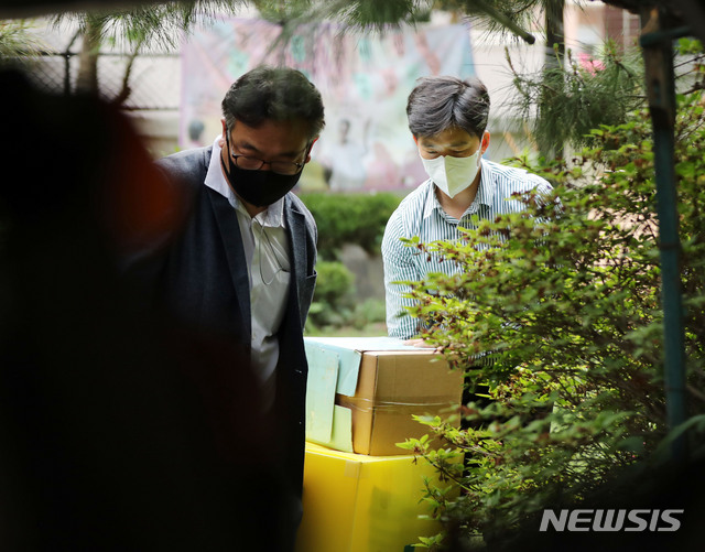 [서울=뉴시스] 박미소 기자 = 검찰 관계자가 21일 오후 기부금 횡령 의혹 등에 휩싸인 정의기억연대(정의연) 수사의 일환으로 피해자 할머니들의 쉼터인 서울 마포구 평화의 우리집에서 압수수색을 마친 후 압수품을 옮기고 있다.2020.05.21.&nbsp; misocamera@newsis.com