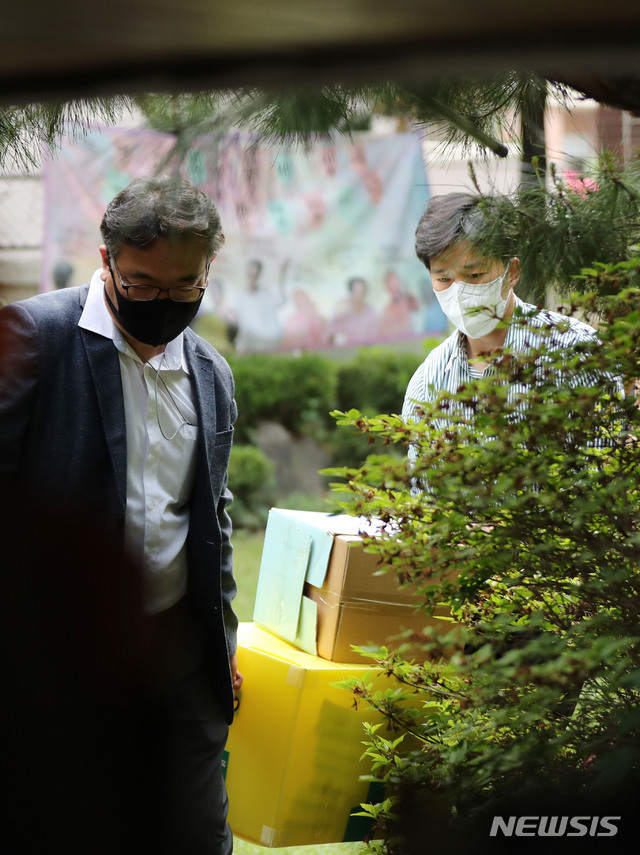 [서울=뉴시스] 박미소 기자 = 검찰 관계자가 21일 오후 기부금 횡령 의혹 등에 휩싸인 정의기억연대(정의연) 수사의 일환으로 피해자 할머니들의 쉼터인 서울 마포구 평화의 우리집에서 압수수색을 마친 후 압수품을 옮기고 있다.2020.05.21.&nbsp; misocamera@newsis.com