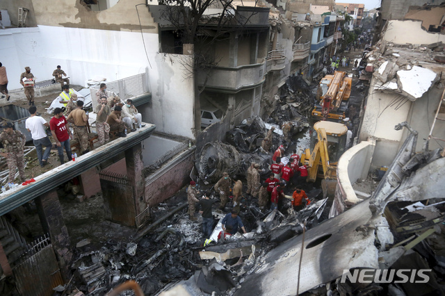 [카라치=AP/뉴시스]자원봉사자들과 군인들이 22일(현지시간) 파키스탄 카라치의 주택가 여객기 추락 현장에서 생존자를 찾고 있다. 2020.05.23.