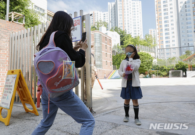 [서울=뉴시스] 박민석 기자 = 전국 고등학교 2학년, 중학교 3학년, 초등학교 1·2학년과 유치원생의 등교가 시작된 27일 오전 서울 성북구 정덕초등학교 입구 앞에서 한 엄마가 등교하는 딸의 기념사진을 찍어주고 있다. 2020.05.27. mspark@newsis.com