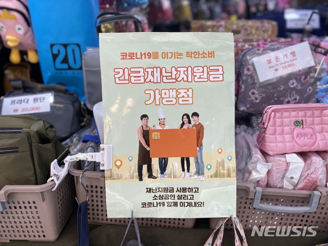 [서울=뉴시스] 이기상 기자 = 29일 오전 서울 중구 남대문시장에 있는 가방가게 가판대 앞에 '긴급재난지원금 가맹점'이라고 적힌 포스터가 붙어 있다. 2020.05.29. wakeup@newsis.com