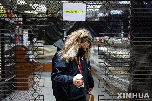 [ 산티아고(칠레)= 신화/뉴시스] 최근 코로나19 확진자 수가 급증하고 있는 칠레의 수도 산티아고에서 마스크를 쓴 여성이 28일(현지시간) 문을 연 가게에서 나오고 있다.   .  