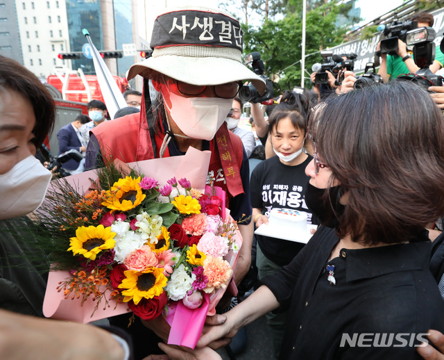 [서울=뉴시스] 전진환 기자 = 삼성항공에 노조를 만들려다 해고돼 복직을 위한 고공농성을 벌여온 김용희씨가 29일 오후 농성을 하던 강남역 사거리 철탑에서 내려와 꽃다발을 받고 있다. 2020.05.29.&nbsp;&nbsp; amin2@newsis.com 