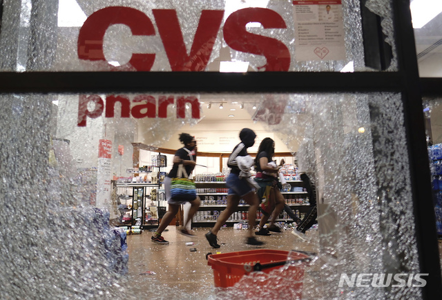 [애틀랜타= AP/뉴시스] 29일(현지시간) 미국 조지아주 애틀랜타에서 비무장 흑인 조지 플로이드가 백인 경찰에게 목이 짓눌려 사망한 사건에 항의하는 시위가 격화했다. 일부 시위대는 경찰서에 불을 지르고 약탈 행위를 하는 등 범법 행위를 저질렀다. 이날 애틀랜타에서 약국 CVS의 깨진 유리창 사이로 사람들이 뛰는 모습이 보이고 있다. 2020.05.30. 