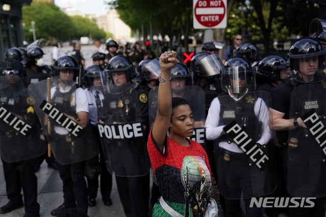  [워싱턴= AP/뉴시스]백악관 주변을 봉쇄하고 있는 워싱턴의 시위 진압 경찰벽 앞에서30일(현지시간) 한 시위대원이 항의의 주먹을 들어보이고 있다. 이 날 시위는 전국 대도시에서 일어났고 워싱턴의 백악관 앞에서는 폭스뉴스 취재진이 군중에게 욕을 먹으며 쫒겨났다. 