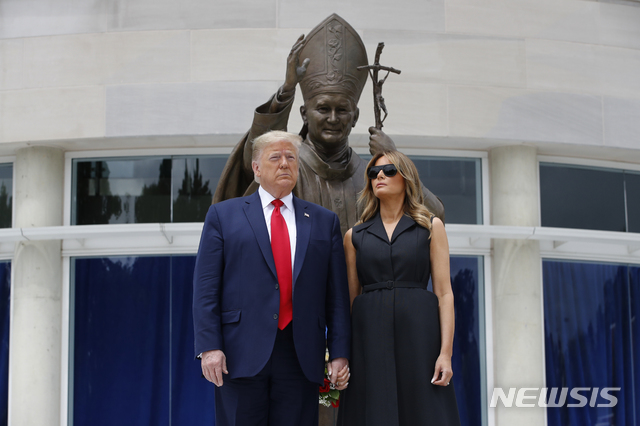 [워싱턴=AP/뉴시스]도널드 트럼프 미국 대통령과 부인 멜라니아 여사가 2일(현지시간) 미 워싱턴DC 내 성 요한 바오로 2세 국가 성지를 방문해 동상 앞에 헌화 후 기념촬영을 하면서 서로 딴 곳을 바라보고 있다. 2020.06.03.
