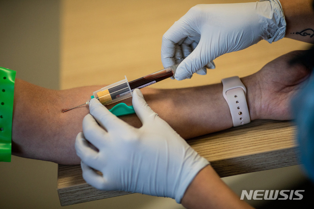 A paramedic, right, takes a blood sample from a front line ambulance worker during an antibody testing program at the Hollymore Ambulance Hub, in Birmingham, England, on Friday, June 5, 2020.  Making antibody tests widely available may help Britain lift its lockdown restrictions, because they show who has already had the COVID-19 and might have a degree of immunity from coronavirus.  (Simon Dawson/Pool via AP)