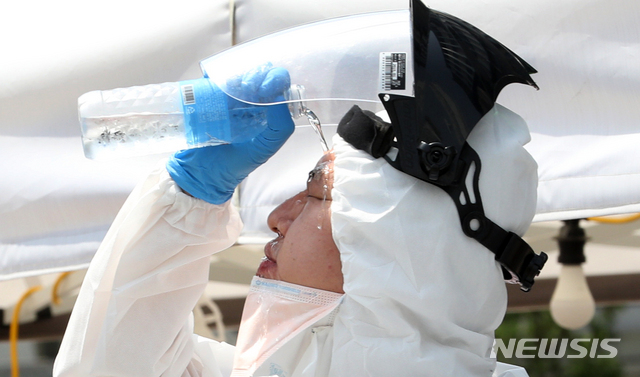 [인천=뉴시스] 이종철 기자 = 신종 코로나바이러스 감염증(코로나19)의 집단감염이 확산되고 무더운 날씨를 보인 지난 8일 오후 인천시 부평구 가톨릭대학교 인천성모병원 선별진료소에서 근무교대를 한 의료진이 얼굴에 물을 뿌리며 더위를 식히고 있다. 2020.06.08. jc4321@newsis.com