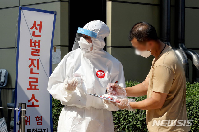 [서울=뉴시스]김병문 기자 = 롯데월드가 지난 5일 중랑구 원묵고등학교 신종 코로나바이러스 감염증(코로나19) 확진 학생의 방문으로 폐쇄된 가운데 8일 오후 서울 송파구 보건소 선별진료소에서 한 시민이 문진표를 작성하고 있다. 2020.06.08. dadazon@newsis.com