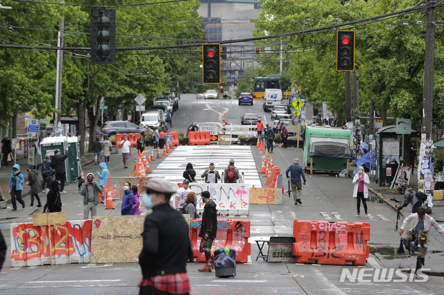 [시애틀=AP/뉴시스]11일(현지시간) 워싱턴 시애틀에서 행인들이 칼 앤더슨 공원 인근 도로에 설치된 바리케이드를 지나고 있다. 2020.06.12.