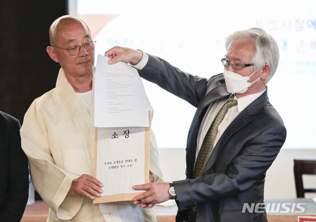 [서울=뉴시스] 박민석 기자 = 명진스님과 소송대리인 변호인단 대표 이덕우 변호사가 15일 오전 서울 중구 우리함께빌딩 '기룬'에서 열린 '국가정보원 민간인 불법 사찰에 따른 명진스님의 국가·조계종 상대 손배소 기자회견'에 참석해 소장을 들어보이고 있다. 2020.06.15. mspark@newsis.com