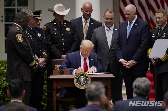 [워싱턴=AP/뉴시스] 도널드 트럼프 미국 대통령이 16일(현지시간) 워싱턴DC 백악관 로즈가든에서 경찰개혁 행정명령에 서명하고 있다. 2020.6.17.
