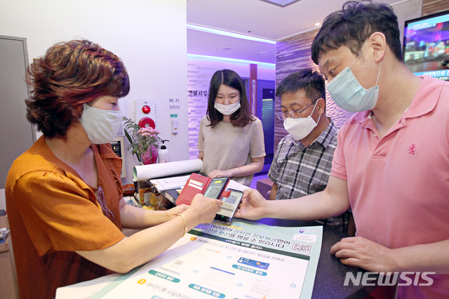 [서울=뉴시스]박주성 기자 = 동작구(구청장, 이창우)가 코로나19 확산 방지를 위한 고위험시설 전자출입명부시스템 사용 의무화에 따라 구청 직원들이 지난달 17일 서울시 노량진동 소재 노래연습장에서 계도 및 점검을 실시하고 이용자가 시설 출입시 스마트기기의 QR코드를 업소관리자의 전용앱을 통해 인식하고 있다. (사진=동작구 제공) 2020.06.17. photo@newsis.com