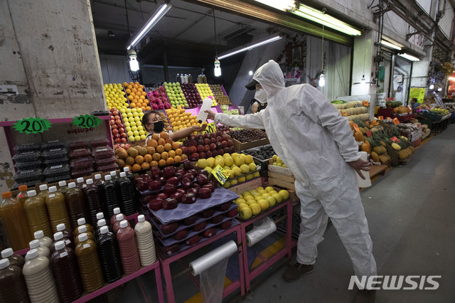 [멕시코시티=AP/뉴시스]멕시코시티의 한 시장에서 18일 신종 코로나바이러스 감염증(코로나19) 확산을 억제하기 위해 보호장비를 착용한 보건요원 1명이 상점 직원에게 손소독제를 건네주고 있다. 멕시코에서 지난 17일 출생한 3쌍둥이가 모두 신종 코로나바이러스 감염증(코로나19)에 감염된 상태로 태어났다고 멕시코 보건 당국이 밝혔다. 2020.6.23