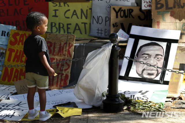 [새크라멘토=AP/뉴시스]19일(현지시간) 미 캘리포니아주 새크라멘토에서&nbsp; '준틴스데이'(Juneteenth Day) 기념 집회가 열린 가운데 2세 소년이 조지 플로이드의 얼굴 그림을 바라보고 있다. 준틴스데이는 1865년 6월 19일 북부군의 고든 그레인저 장군이 북부군을 이끌고 미 텍사스주 갤버스턴에 도착해 흑인들의 노예 해방령을 선포한 날로 에이브러햄 링컨 대통령이 1863년 노예 해방령에 서명한 지 2년 만에 사실상 노예제가 종식된 날이다. 2020.06.20.