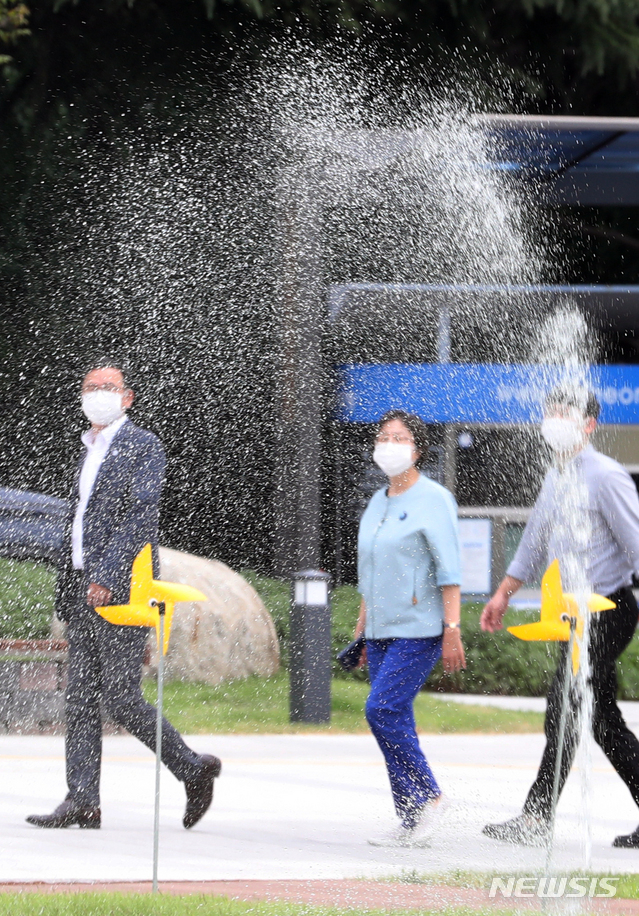 [인천=뉴시스] 이종철 기자 = 폭염이 이어지는 지난 23일 오후 시민들이 인천시 남동구 인천시청앞 잔디에 물을 주는 스프링클러 옆을 지나치며 더위를 식히고 있다. 2020.06.23. jc4321@newsis.com
