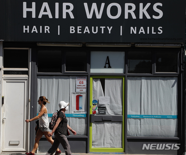 [런던=AP/뉴시스]23일(현지시간) 영국 런던의 한 미용실 앞을 행인들이 지나가고 있다. 영국은 신종 코로나바이러스 감염증(코로나19) 억제를 위해 미용실, 음식점, 술집 등의 영업을 제한 중이다. 2020.6.23.