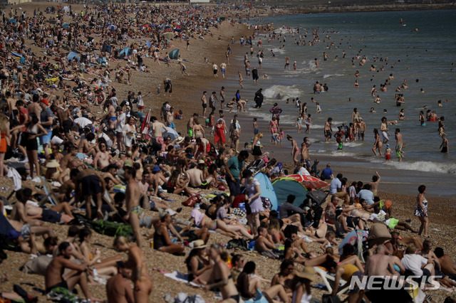 [브라이튼=AP/뉴시스]영국 히스로의 최고 기온이 32.6도까지 오르는 등 영국에서 가장 더운 날을 기록한 24일(현지시간) 영국 브라이튼의 브라이튼 해변에 사람들이 모여 더위를 피하고 있다. 영국에서 7월 4일부터 신종 코로나바이러스 감염증(코로나19) 규제가 완화되는 가운데 사람들이 밀폐된 공간에서 마스크를 착용하는 등 코로나19 재발 방지 활동에 힘쓴다면 사회적 거리 두기는 기존 2m에서 최소 1m로 완화된다. 2020.06.25.