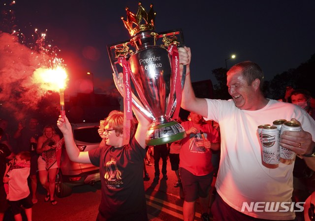 [리버풀=AP/뉴시스]잉글랜드 프로축구 프리미어리그(EPL) 리버풀의 지지자들이 25일(이하 현지시간) 영국 리버풀의 안필드 스타디움 밖에 모여 모조 우승컵을 들고 리버풀의 EPL 우승을 축하하고 있다. 리버풀은 24일 크리스털 팰리스에 4-0 완승하며 우승 초읽기에 들어갔었고 이어 맨체스터시티가 첼시에 패하면서 우승을 확정 지었다. 이로써 리버풀은 EPL 출범 후 첫 우승을 차지하게 됐다. 2020.06.26.
