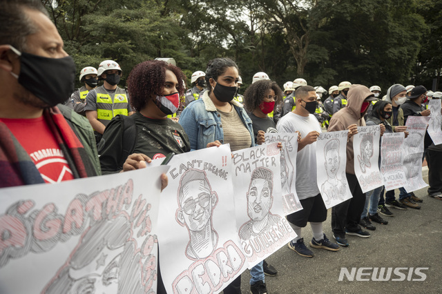 [상파울루=AP/뉴시스] 브라질 정부와 보우소나루 대통령의 잘못된 코로나19 대응정책에 항의하는 시위대.  이들이 들고 있는 것은 지난 달 28일 항의시위에서 경찰 폭력에 희생된 청년들과 학생들의 초상화이다.    