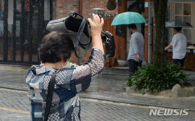 [전주=뉴시스] 김얼 기자 = 전북지역에 정체전선의 영향으로 비가 내린 29일 전북 전주시 전주한옥마을에서 한 관광객이 가방으로 비를 피하며 발걸음을 재촉하고 있다. 2020.06.29.pmkeul@newsis.com