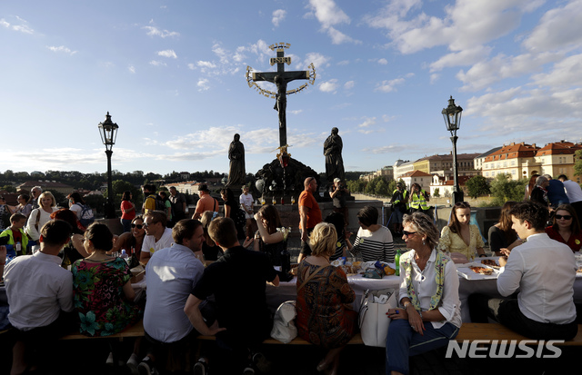 [프라하(체코)=AP/뉴시스]체코 프라하에서 지난달 30일 신종 코로나바이러스 감염증(코로나19) 확산 억제를 위해 실시됐던 강력한 규제 조치 종료를 축하하기 위해 길이 1600피트(약 488m)에 달하는 대형 테이블이 설치된 카를 다리 위에서 시민들이 준비해온 술과 음식을 마시며 축하하고 있다. 2020.7.2