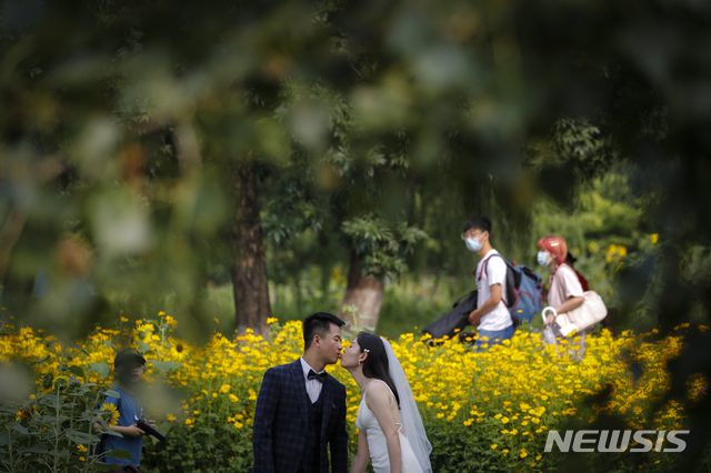 [베이징=AP/뉴시스] 2020년 7월2일 중국 베이징 올림픽숲 공원에서 한 신혼부부가 야생화를 배경으로 결혼사진을 찍고 있다. 2020.07.02. * 기사 내용과 관련 없음 