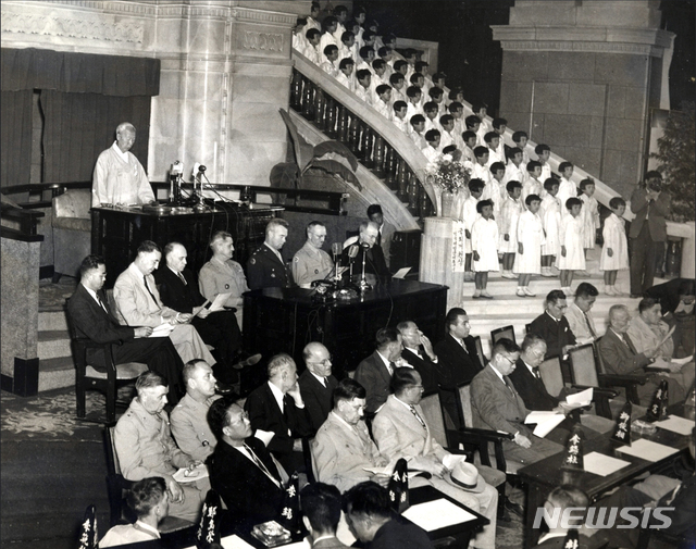 [서울=뉴시스] 1948년 5월 31일 오후 2시 미 군정청 내 국회의사당에서 개최된 제헌국회 개원식에서 개회사를 하는 이승만(李承晩) 국회의장. 이승만은 오전에 개최된 제1차 본회의에서 의장으로 선출됐다. 이승만 국회의장 앞에 외빈들이 앉아 있다. 왼쪽 두번째부터 주한미군사령관 하지 중장의 경제고문 아서 번스(Arthur Bunce) 박사, 정치고문 조셉 제이콥스(Joseph E. Jacobs), 하지 중장, 군정장관 윌리엄 딘((W. Dean) 소장, 헬믹 소장, 교황청 사절 패트릭 번(Patrick J. Byrne) 신부. (사진=미국 국립문서기록청) 2020.07.05. photo@newsis.com (* 위 사진은 재배포, 재판매, DB 및 활용을 금지합니다)