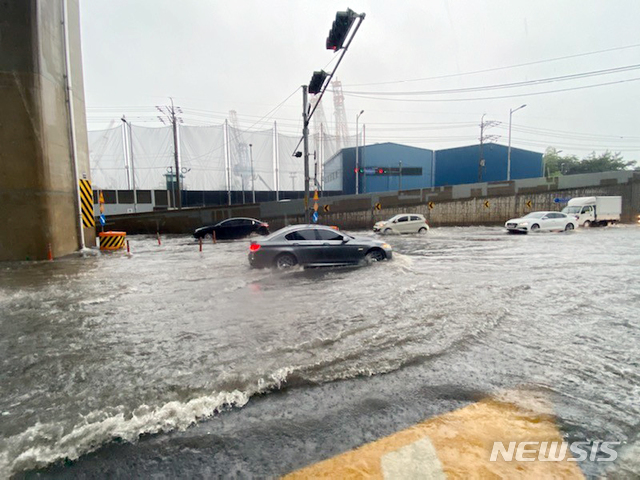 [부산=뉴시스] 부산지역에 호우경보가 발효된 10일 오전 영도구의 한 아파트 앞 도로가 침수돼 차량들이 함겹게 이동하고 있다. (사진=부산소방재난본부 제공). 2020.07.10.&nbsp; photo@newsis.com&nbsp; 