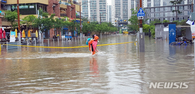 [부산=뉴시스] 부산지역에 호우경보가 발효된 10일 연제구의 한 아파트 앞 도로에서 소방대원이 한 어린이를 업고 침수된 도로를 건너고 있다. (사진=부산소방재난본부 제공). 2020.07.10.&nbsp;&nbsp;&nbsp; photo@newsis.com&nbsp; 