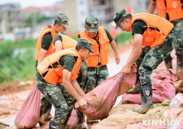 [포양현(중 장시성)=신화/뉴시스] = 12일 홍수피해가 발생한 장시성 상라오시 포양현에서 군인들이 긴급 방재작업을 진행하고 있다. 최근 집중호우가 이어지고 상류에서 내려오는 포양호 수위도 급상승했고, 일부 관측 지점의 수위는 종전 최고였던 1998년의 기록보다 더 높아졌다. 2020.07.13 