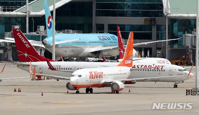 [인천공항=뉴시스] 이영환 기자 = 제주항공이 이스타항공에 통보한 인수합병(M&A) 선결 조건 이행 시한을 하루 앞둔 14일 오전 인천국제공항 여객터미널에 제주항공 비행기와 이스타항공 비행기가 멈춰 서 있다. 항공업계에 따르면 제주항공은 지난 1일 이스타항공에 "영업일 기준 10일 안에 미지급금 해소 등 선결조건을 이행하지 않을 시 계약을 파기할 수 있다"는 내용을 담은 공문을 보냈으며 이스타항공이 15일까지 250억원가량의 체불임금을 포함한 1700억원대의 미지급금을 갚아야 한다는 의미다. 2020.07.14. 20hwan@newsis.com
