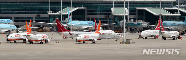 [인천공항=뉴시스] 이영환 기자 =  제주항공이 이스타항공에 통보한 인수합병(M&A) 선결 조건 이행 시한을 하루 앞둔 14일 오전 인천국제공항 여객터미널에 제주항공 비행기와 이스타항공 비행기가 멈춰 서 있다. 항공업계에 따르면 제주항공은 지난 1일 이스타항공에 "영업일 기준 10일 안에 미지급금 해소 등 선결조건을 이행하지  않을 시 계약을 파기할 수 있다"는 내용을 담은 공문을 보냈으며 이스타항공이 15일까지 250억원가량의 체불임금을 포함한 1700억원대의 미지급금을 갚아야 한다는 의미다. 2020.07.14. 20hwan@newsis.com